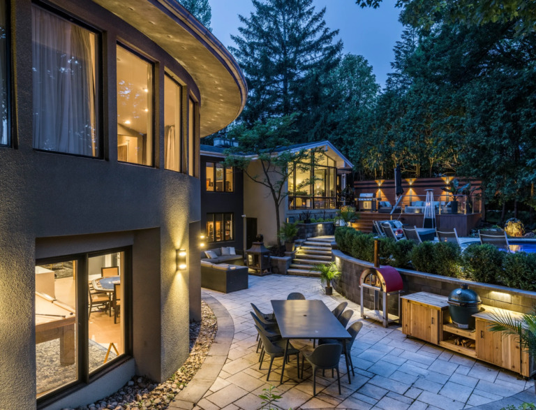 View of a modern villa entrance with clean lines and large glass panels, inspired by 1980s architecture.