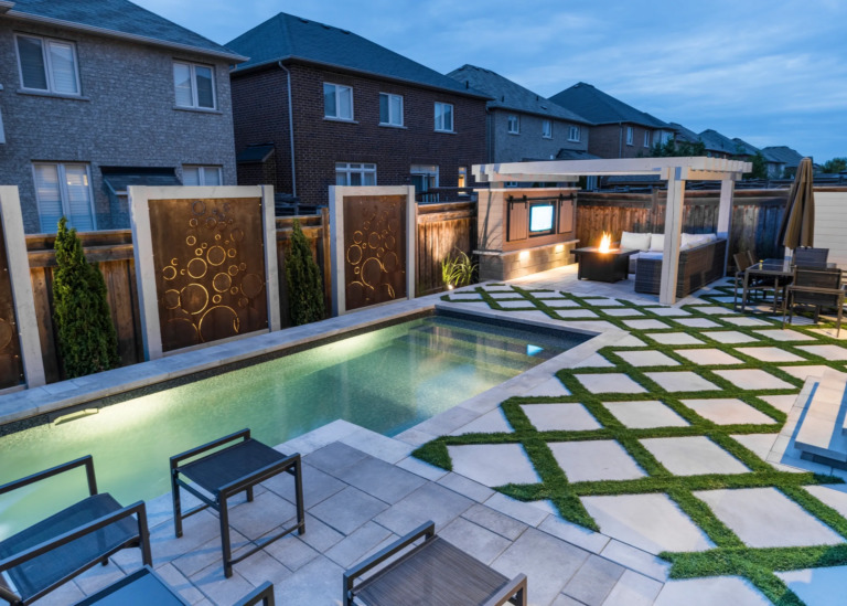Beautiful backyard with a swimming pool, stone patio, and lush greenery.