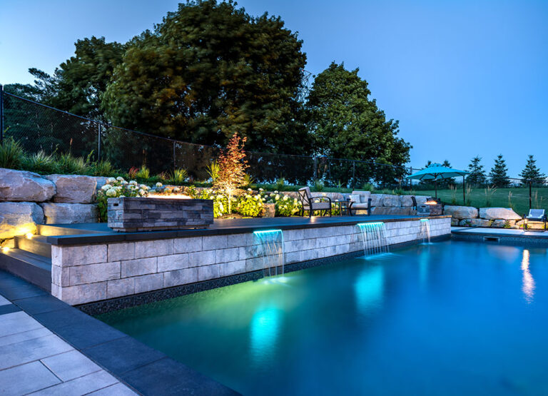 Close-up of a luxurious pool with intricate stonework and adjacent garden space.