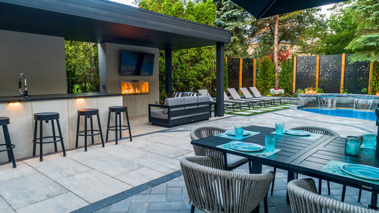Aerial view of a luxury backyard featuring a pool, patio, and greenery.
