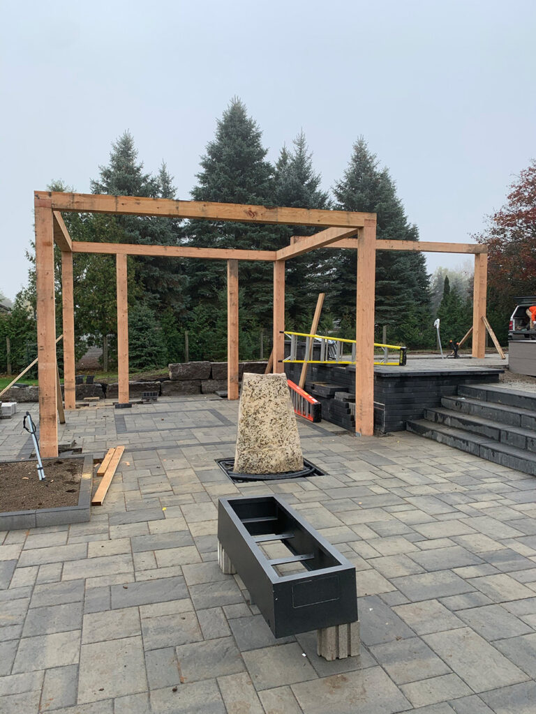 Backyard pool area with lush greenery and modern stone patio design.