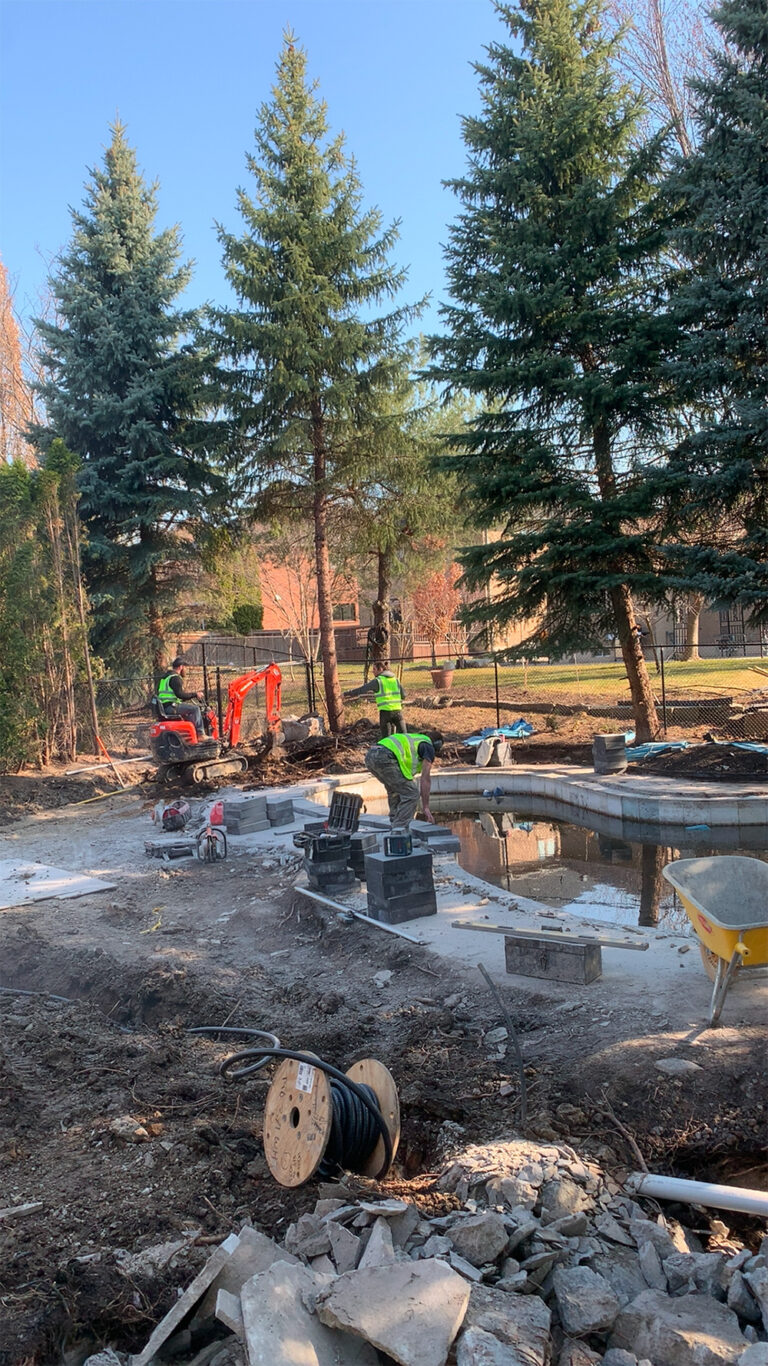 Deer Chase backyard - wide view of modern pool, stone patio, and surrounding landscaping.