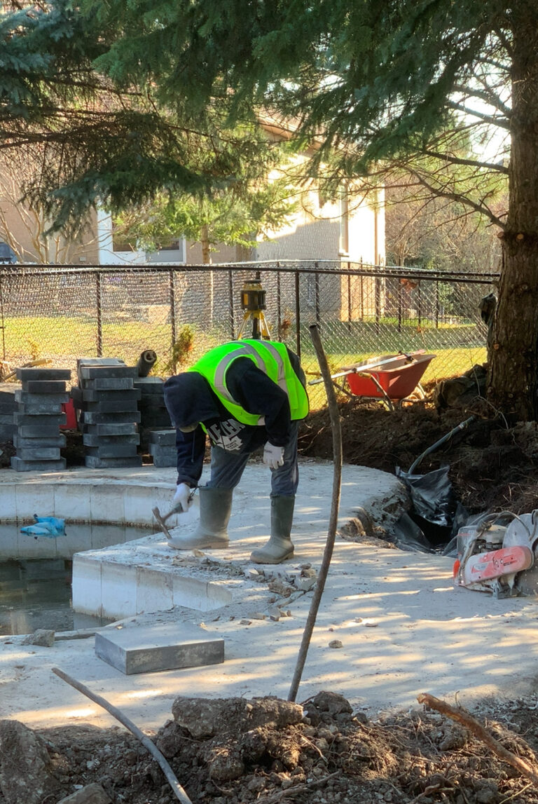 Deer Chase backyard - poolside view with elegant stone deck and well-maintained lawn.
