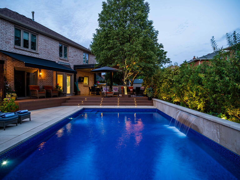 Modern backyard with a sleek pool, patio, and surrounding greenery.