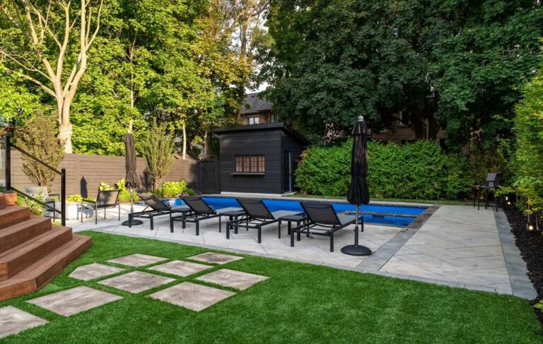 Outdoor space with pool, wooden deck, and surrounding greenery in a modern backyard.