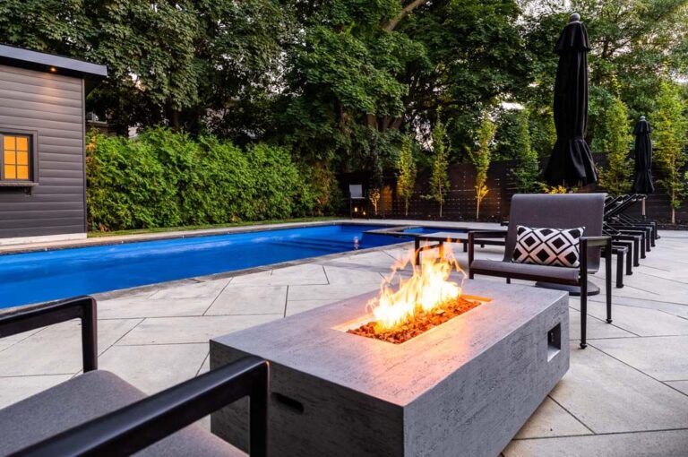 Luxury poolside area with wooden deck and outdoor furniture in a modern backyard.