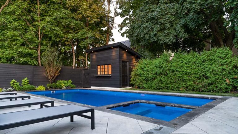 Beautifully designed backyard with wooden deck, modern pool, and lounge chairs.