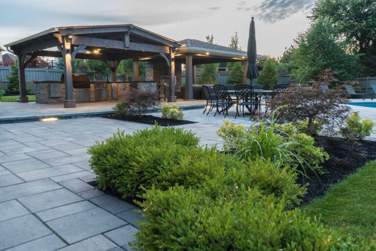 Well-maintained backyard with stone patio and greenery