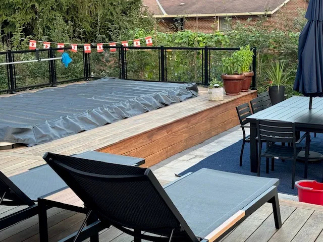 Backyard deck and dining area overlooking a covered swim spa in Toronto